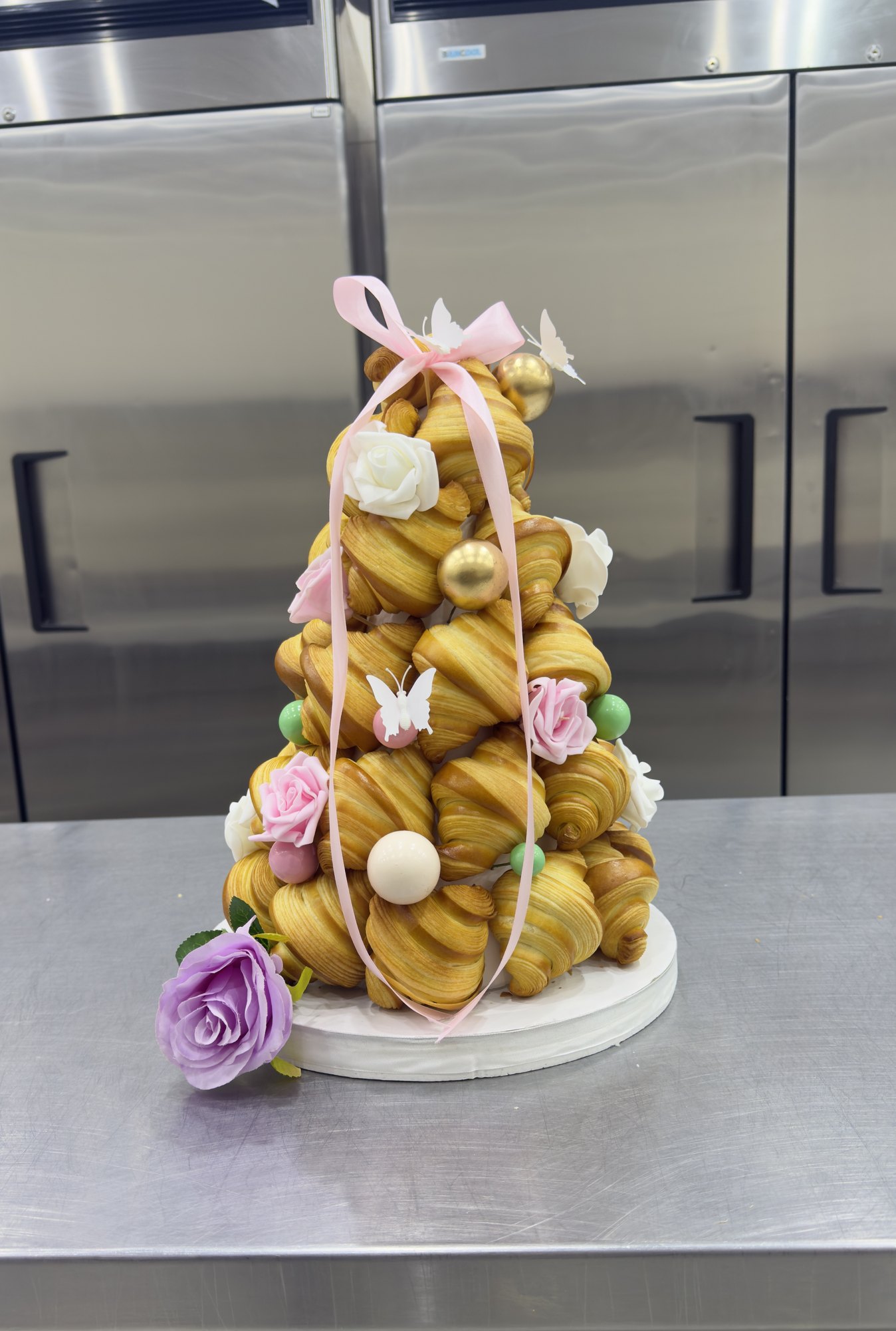 A croquembouche tower decorated with flowers and ribbon
